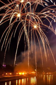 Flash of fireworks in night sky over river in city. Holiday concept. Close-up