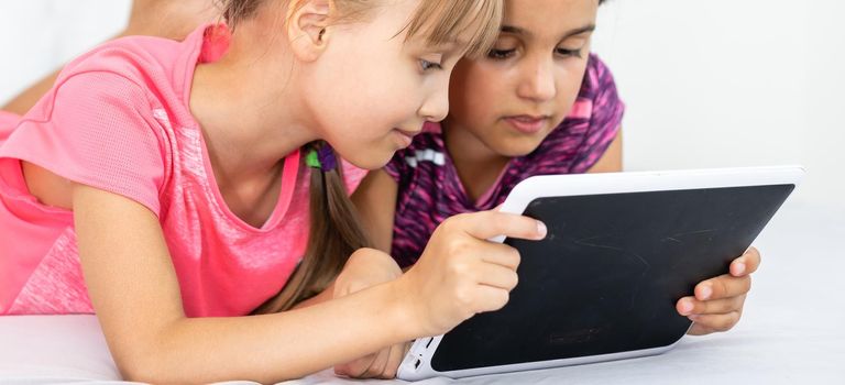 people, children, technology, friends and friendship concept - girls looking to tablet pc computers at home.