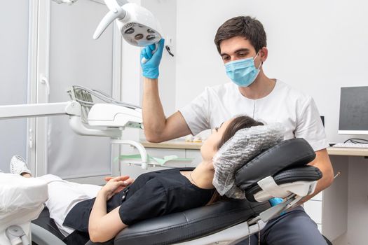 Dentist adjusting dental lamp in a dental office