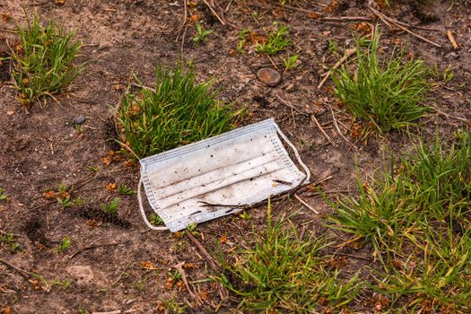 A surgical mask lost in the COVID-19 pandemic pollutes the environment in a field