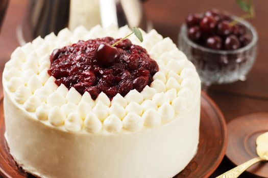 Biscuit cake, cherry souffle with cream cheese and cherry confiture on wooden background. Close-up