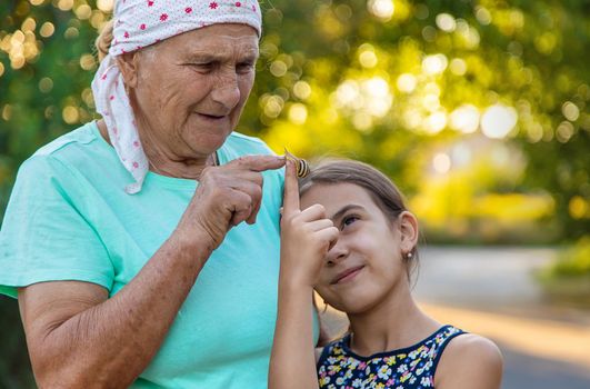 Grandmother and child are studying the snail in the park. Selective focus. Nature.