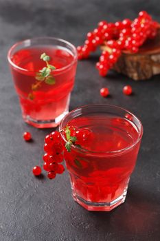 Redcurrant vitamin drink in a glass on a black background with currant berries. healthy eating