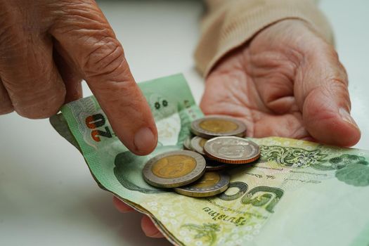 Retired elderly woman counting coins money and worry about monthly expenses and treatment fee payment.