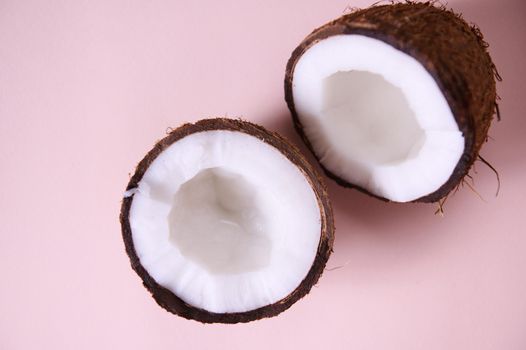 Still life. Close-up of halves of ripe organic raw vegan coconuts, shot with soft shadow isolated on pink background with copy space for promotional text. Exotic tropical palm fruits. Healthy eating