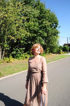 young beautiful caucasian girl walks with two dogs on the road among tall trees in summer. High quality photo