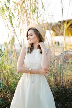 Young woman in a straw hat stands with a cane branch in her hand. High quality photo