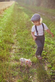 The little traveler met a piglet in the field. Retro photo.