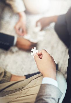 Hes got the final piece. High angle shot of an unrecognizable businessman holding a puzzle piece during a meeting