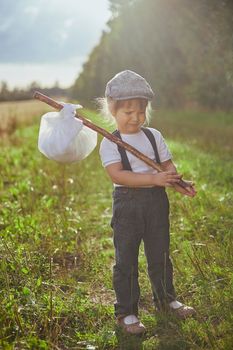 Beautiful sad street child in a field at sunset.