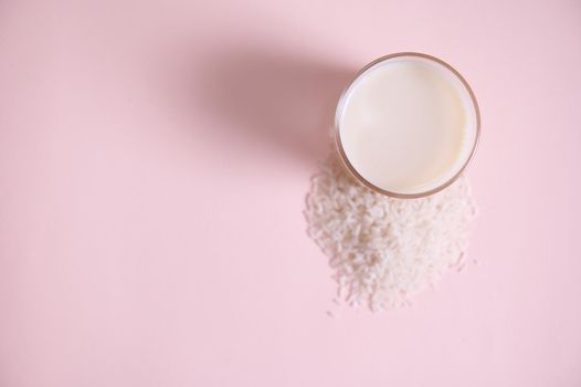 Flat lay. Still life with food and drink. Top view drinking glass of fresh organic, raw vegan, vegetable rice milk on pink background with copy advertising space. Healthy eating and veganism concept