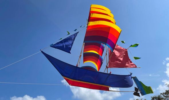 flying ship, rainbow colored ship kite flies on the blue sky and cloud in the beach