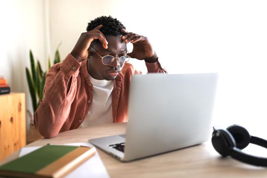 African American black male college student stressed and overwhelmed studying in front of laptop. Education concept.