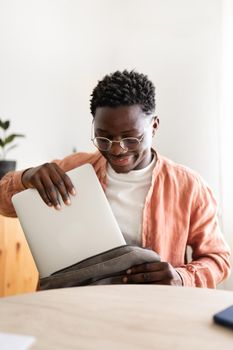 Black male college student taking laptop out of backpack to start doing homework at home. Vertical image. Education concept.