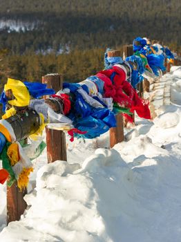 Colorful traditional prayer flags hanging out in wind at snowy temple complex at cold winter, asian culture at local monastery, vertikal image of no people mountain landscape