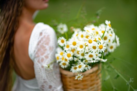 A middle-aged woman holds a large bouquet of daisies in her hands. Wildflowers for congratulations.