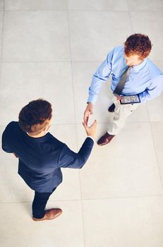 Its a pleasure to welcome you to our company. High angle shot of two businessmen shaking hands in an office