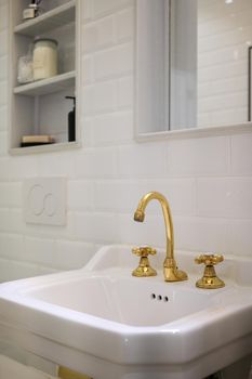 Close up shot of a vintage two handle faucet in a bathroom with white tiles. Copper retro styled water mixer