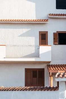 Typical white house facade part in italian city near the sea. Brown windows on white wall. Mediterranean village style architecture.