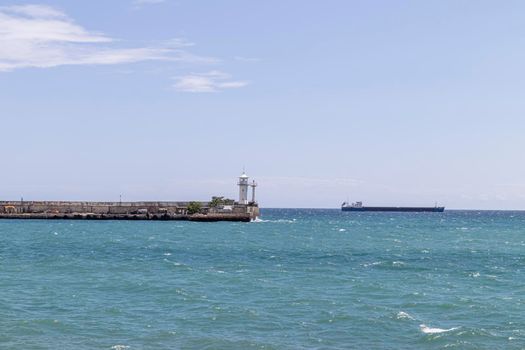 lighthouse on the pier and cargo ship. photo