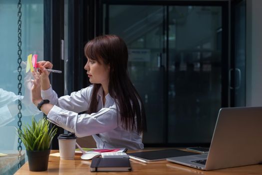 Asian Business woman taking note on sticky note.