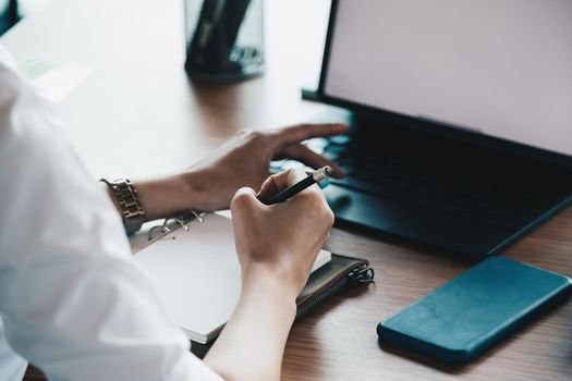 Cropped of woman hand taking notes with laptop at the table office.