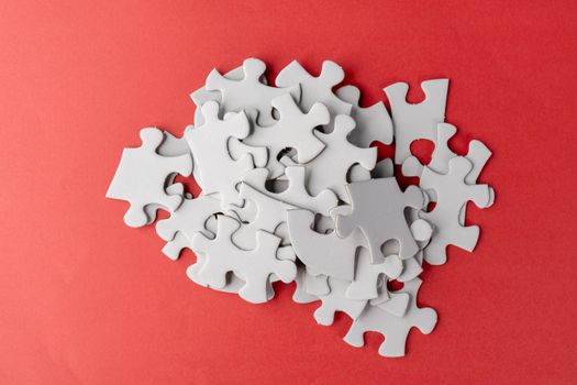 Stack of white jigsaw puzzle on red background