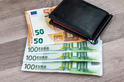 50 and 100 euro banknotes with wallet on wooden top