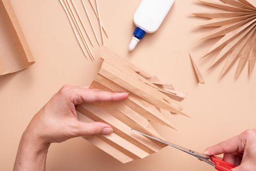 Cutting out the pointed parts of a palm leaf. Creative handwork to create tropical leaves. Master class.