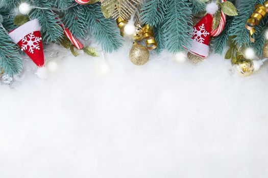 Frame made of fir branch and Christmas decorations flat lay on a snowy background with copy space
