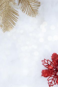 Winter vertical background with golden branches and a red poinsettia in glitter and bokeh with copy space Christmas and New Year background