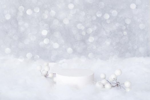 Podium mock-up for cosmetics in the snow with decorative berries on a bokeh background. Cristmas presentation of your products.