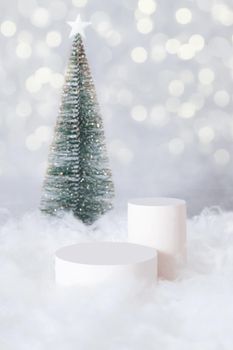 Podium or pedestal mok-up for cosmetics in the snow with a christmas tree on a bokeh background vertical format