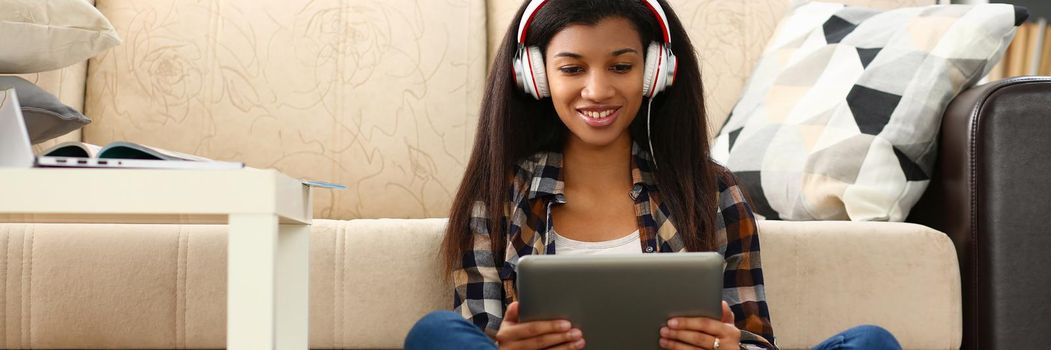 African american woman in headphones looking at digital tablet at home. Pastime on during lockdown concept