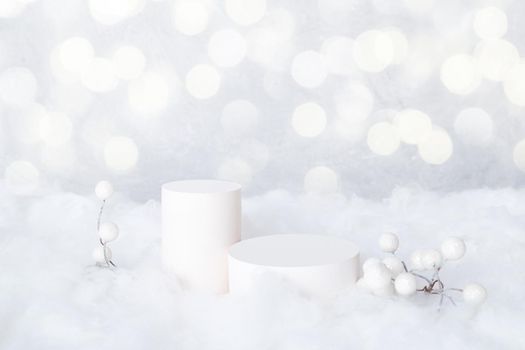 Mock-up podiums for cosmetics in the snow with decorative berries on a bokeh background