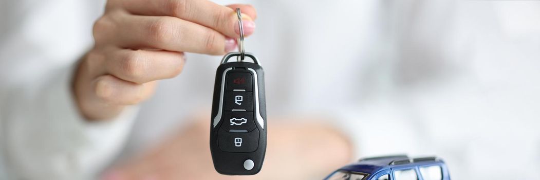 Dealer holding keys in front of toy car and money closeup. Sale and rental of cars concept