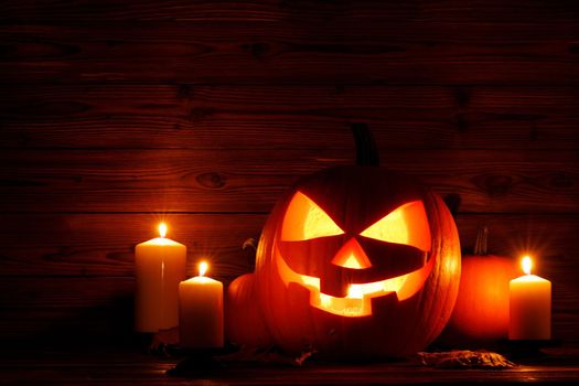Halloween night glowing pumpkins and candles on wooden background
