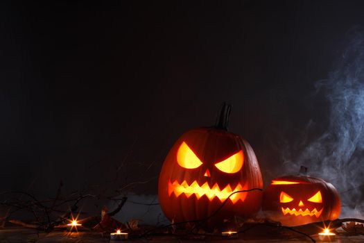 Halloween Jack O Lantern pumpkins and burning candles in mist traditional decoration