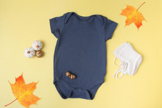 Baby clobodysuit mock-up top view with pumpkins on yellow background for your text or logo place in autumn season