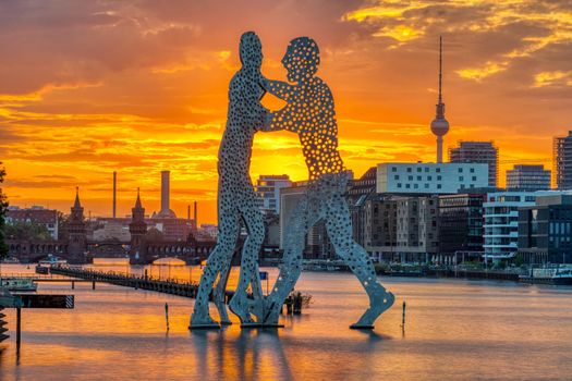 Sunset in Berlin with the river Spree, the Molecule Men sculpture and the TV Tower