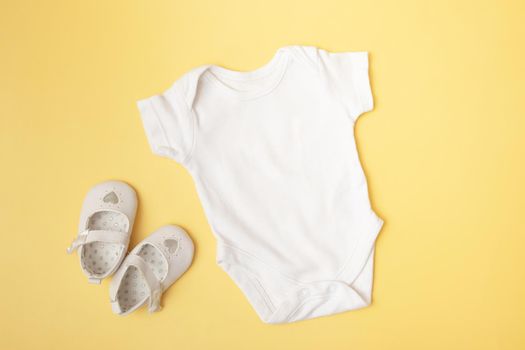 Baby clobodysuit mock-up top view with pumpkins on yellow background for your text or logo place