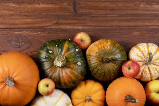 Different pumpkins on a wooden background, autumn theme, texture. Design ideas, top view. Halloween, Thanksgiving day