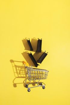 Flat lay miniature supermarket cart with shopping bags in black friday sale