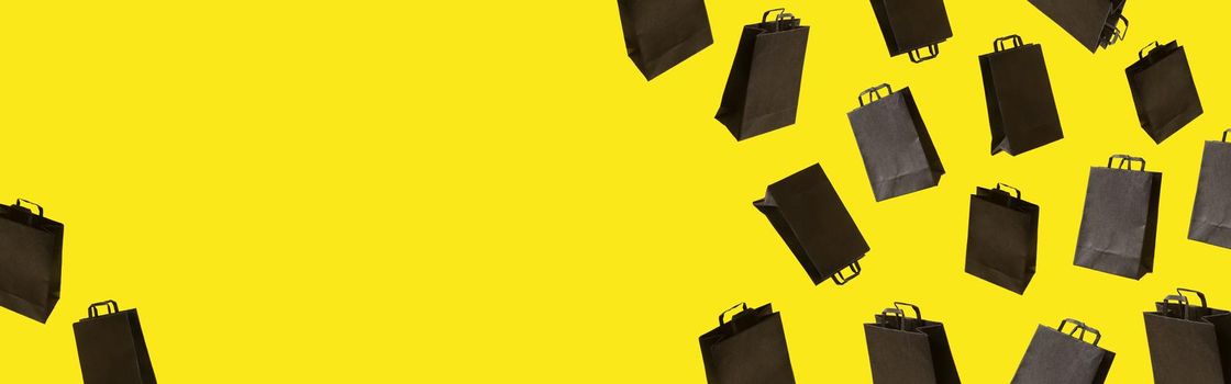 Banner with black sale shopping bags are flying on yellow background. Black Friday creative idea concept