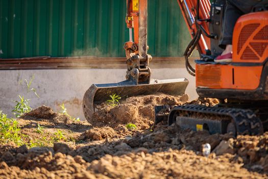A minitractor rakes the earth with a bucket. Land works