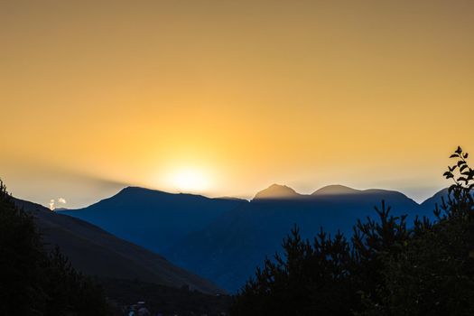 Sunrise in the mountains. Black silhouettes of mountain peaks.