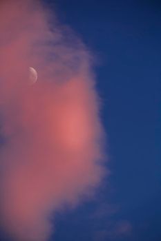 Crescent moon between pink clouds on blue sky in southern Spain in summer