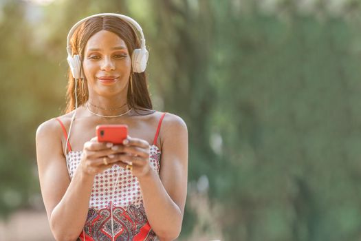 Portrait with copy space of a Transgender woman listening to music with the mobile outdoors