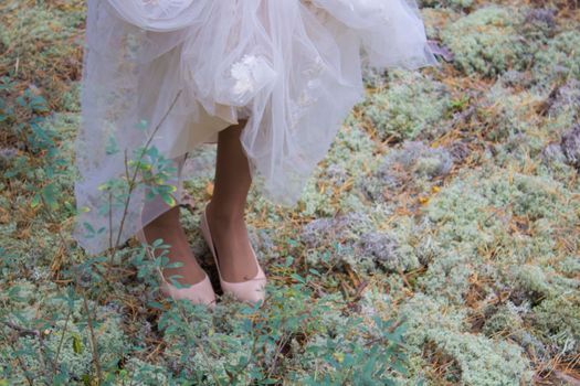 Bride walks carefully over the moss in the forest. Beauty, softness, elegance
