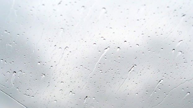 close-up, drops of water on the windshield of the car, while driving. From a strong wind, droplets flow down the glass, not down, but upwards. High quality photo